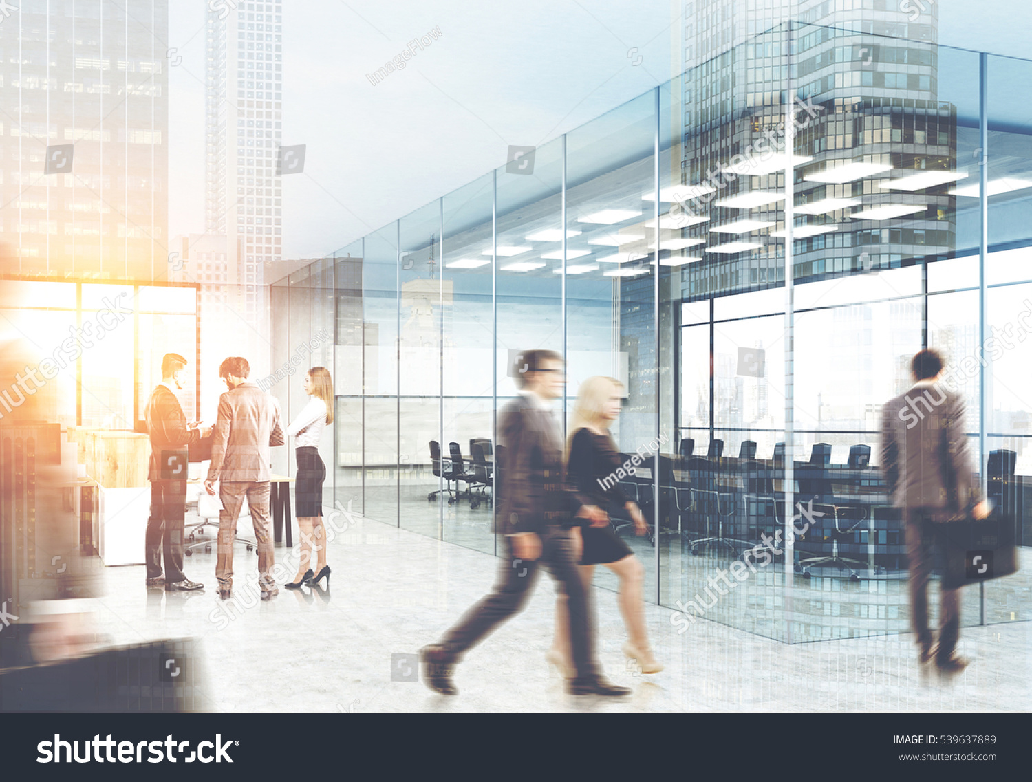 stock photo view of men and women in suits walking in a glass office city view is seen on the foreground 539637889